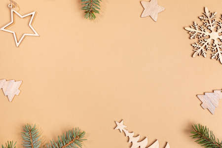 Christmas or New Year beige background with frame of wooden festive decorations - Xmas toys and fir tree twigs with copy space in center. Top view. Horizontal orientation.の写真素材