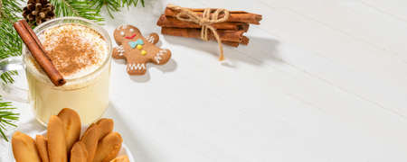 Christmas banner with traditional holiday drink homemade creamy eggnog with cinnamon and ginger cookies on white wooden backdrop. Typical Xmas dessert. Copy space for text.の写真素材