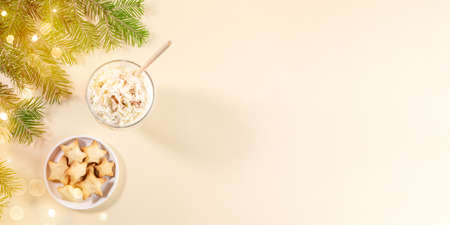 Xmas banner with holiday desserts. Christmas traditional eggnog, ginger cookie stars, green fir branches, Xmas bokeh lights on beige neutral with copy space. Festive baking and drink. Top view.の写真素材