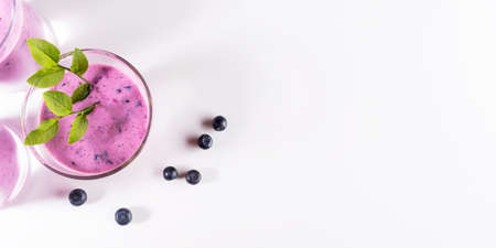 Glasses of blueberries smoothie on white. Healthy drink is antiviral, useful for immunity, reducing sugar, excess weight, depression. You can also use vegetable milk. Banner. top view. copyspace.の写真素材