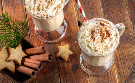 Eggnog with whipped cream and cinnamon, Xmas cookies stars, fir twig on old wooden table....