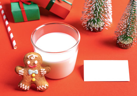 Milk for Santa concept. Milk glass, gingerbread man, empty white note, gift boxes, drinking straw...