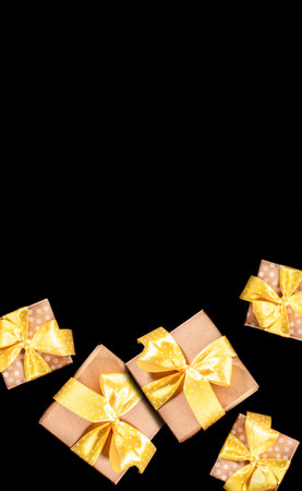 Gift boxes decorated with yellow polka dot ribbons and bows on black background. Holiday and sales...