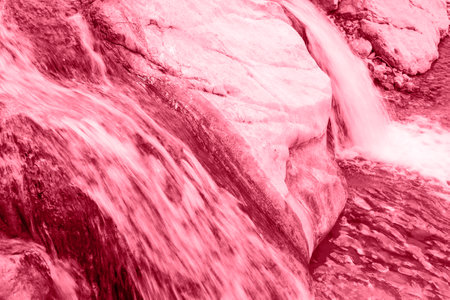 Close up small waterfall on a stone mountain river. long exposure. Trendy toning in color 2023 Viva Magenta.の写真素材