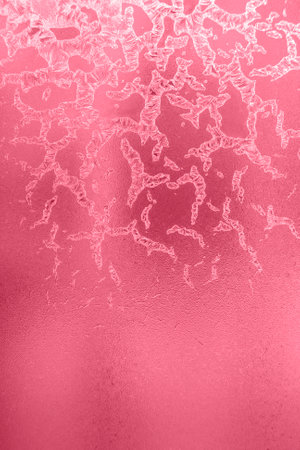 Winter frosty pattern. Bizarre drawing of ice crystals on frozen winter window. Christmas or New Year background. Trendy toning in color 2023 Viva Magenta. vertical orientation.の写真素材