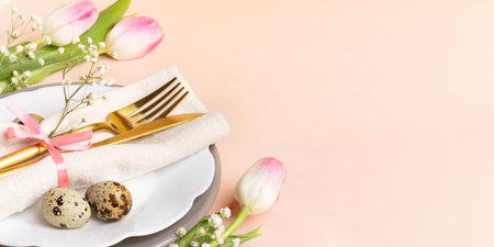 Festive Easter table decoration idea in peach-pink colors. Golden cutlery, quail eggs, napkin,...