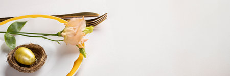 Easter banner. Golden egg in nest, delicate peach Eustoma flower on white and yellow plates, gold...