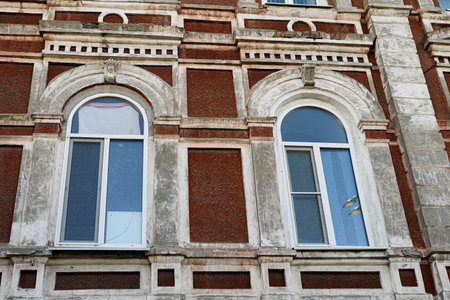 Architectural detail showcasing vintage building with arched windows, textured brick facade, and...