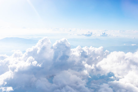 Expansive view from airplane showcasing fluffy white clouds floating in bright blue sky, with soft sunlight illuminating scene, creating serene and tranquil atmosphere inopen skyの写真素材
