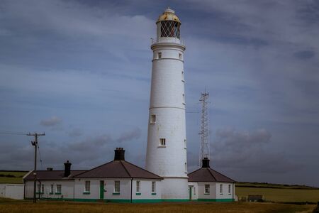 The coast of Wales with a historic lighthouse among green meadows.の写真素材