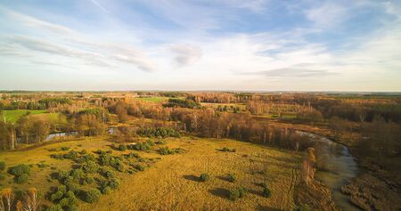 Small river in central Poland, flowing among green meadows and forests.