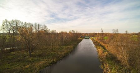 Small river in central Poland, flowing among green meadows and forests.