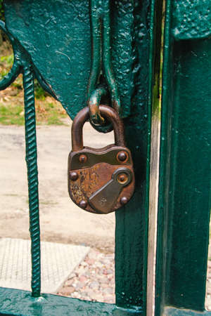 Locked old, antique padlock on the green gate.