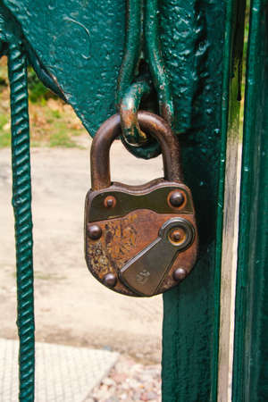 Locked old, antique padlock on the green gate.の写真素材