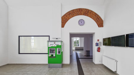 Interior of an empty hospital with a green ticket vending machine.