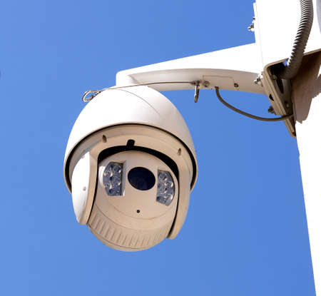 High resolution oval shape video surveillance camera on the street on blue sky background
