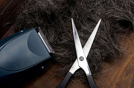 A hair clipper, scissors and cut gray hair on wooden backgroundの写真素材