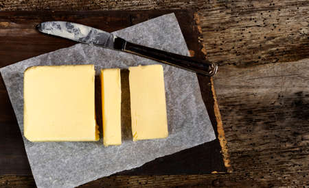 top view of butter cut with a knife on wooden backgroundの写真素材