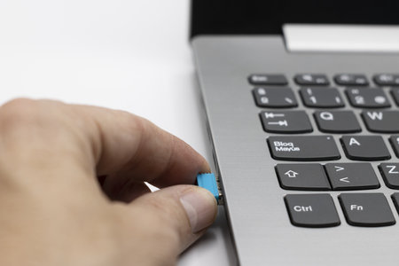 A person inserts a usb wifi stick into a laptop, communications concept