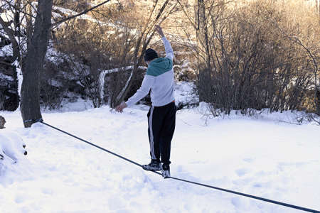 A young teenager balances a tightrope in the snow