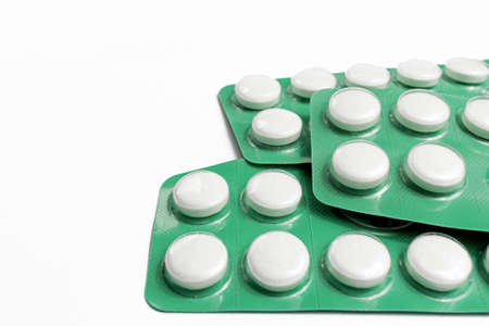 Three green blister packs with white tablets of acetylsalicylic acid for the symptomatic relief of...