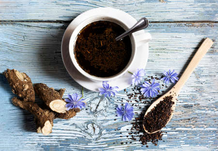 Healthy coffee substitute infusion made with chicory root, the root, the flower and a cup are displayed on a bluish wooden backgroundの写真素材