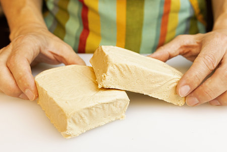a person in the kitchen wearing a green apron prepares the meal by cutting a block of tofu into...