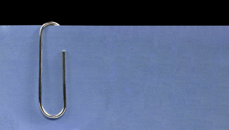 Nickel plated office clip holding a blue paper, office suppliesの写真素材