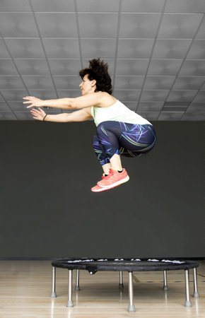 Athletic Woman Jumping High on a Fitness Trampoline During an Intense Indoor Workout Session