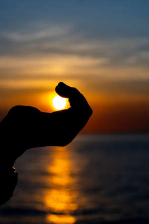 Sun in the hand of a woman at sunsetの写真素材