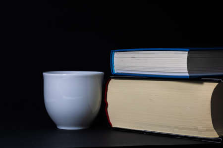 Books and a cup on the black backgroundの写真素材