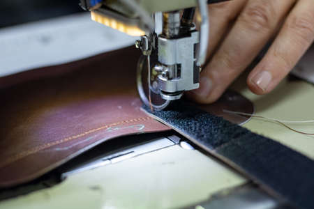 shoemaker sewing the leather on shoe sewing machine in workshop