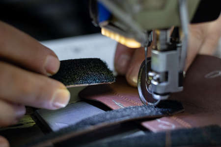 shoemaker sewing the leather on shoe sewing machine in workshopの写真素材