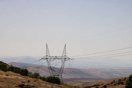 High Voltage Electricity lines over the hills at daytime. Electricity pylons on the hills.の写真素材
