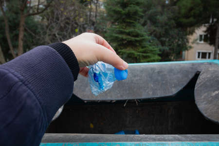 Man throwing a plastic bottle to the recycling bin. Environmental pollution. recycling background photo. Clean cities.の写真素材