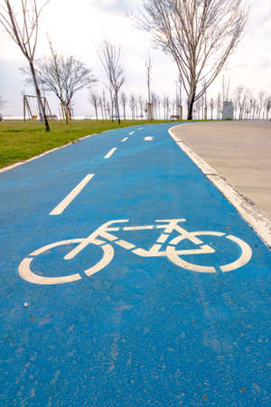 Bike road in the park. Healthy lifestyle. Bicycle track. Bike road sign on blue background.の写真素材
