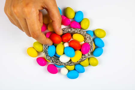 Woman picking a candy in candy bowl in focus on white background. Eid al fitr or eid al adha...