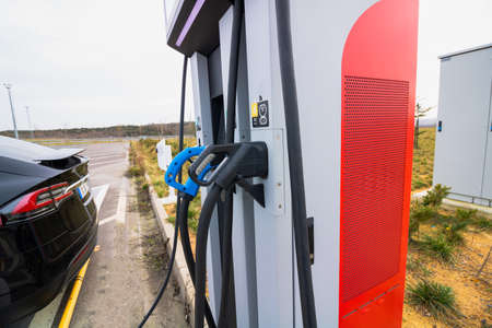 EV car plugged in charger and EV Charger station. Electric car charger station near the highway. Electric car. Zero emission car charging. Carbon freeの写真素材