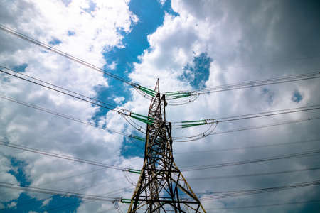 Electricity transmission towers or pylons with cables and cloudy sky on the background. High voltage current transmission. Industrial or electricity transmission background. Power lines from below.の写真素材