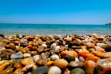 Selective focus of pebbles on the seashore and wavy sea on the background. Pebble sea shore. Vacation, holiday, tourism background.の写真素材