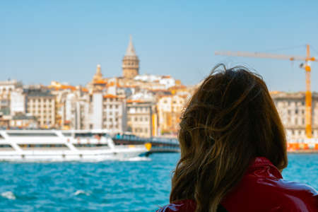Woman looking to Istanbul. Young woman on the boat looking to Galata Tower. Tourists or tourism in Istanbul. Traveling to Turkey.の写真素材