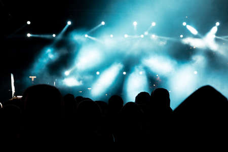 concert background. Silhouette of crowd in the concert background photo. Spotlights or stage light and foggy effect. NOISE EFFECT.の写真素材