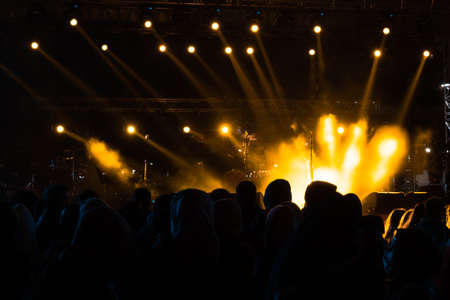 concert background. Yellow spotlights on the stage and silhouette of people. Concert or event background photo. Noise effect included.の写真素材