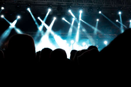 concert background. Foggy effect and spotlights on the stage. Silhouette of people in the concert....