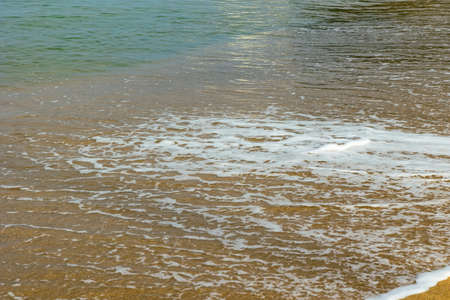Wave foams on the beach. Vacation or holiday or travel background photo. Selective focus or motion...