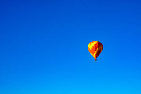 Hot Air Balloon. Single red and yellow colored hot air balloon isolated on clear blue sky background. selective focus.の写真素材