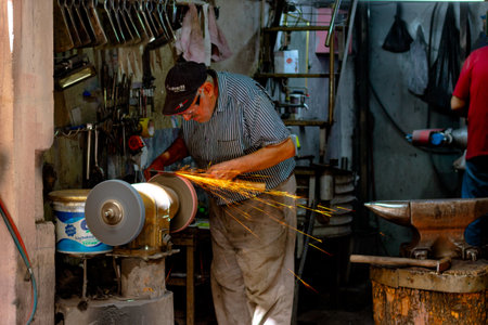 Craftsman honing or sharpening a blade on the machine. Using a blade to sacrifice for eid al-adha or Kurban Bayrami in Turkish Culture. Malatya Turkey - 7.14.2021のeditorial素材