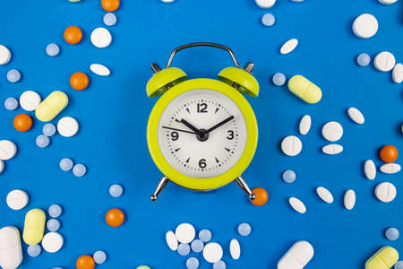 Medical pills with alarm clock. Taking pills or capsules on time concept photo. Remembering to take...
