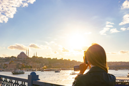 Travel to Istanbul. Tourist woman taking a photo of Istanbul at sunset. Travel to Turkey or Turkiye background photo.の写真素材