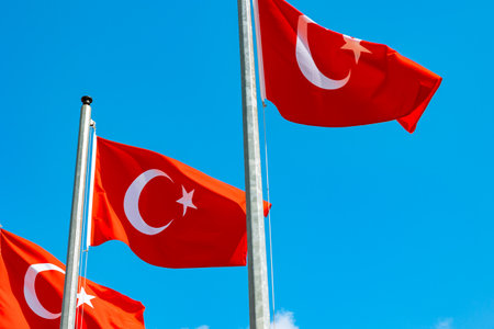 Three Turkish flags waving on the flagpole isolated on blue sky background. Turkish national holidays background photo.の写真素材